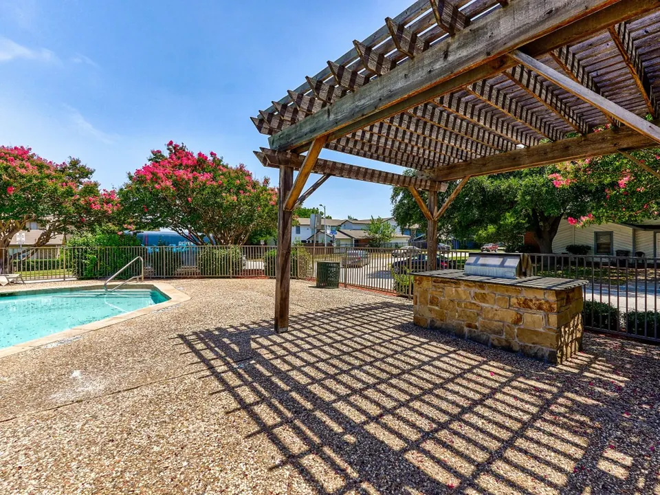 Covered grill area under a pergola by the pool