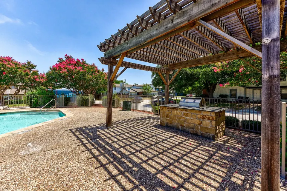 Covered grill area under a pergola by the pool