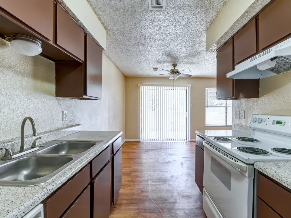Kitchen with dark wood cabinets, a double sink and a patio door