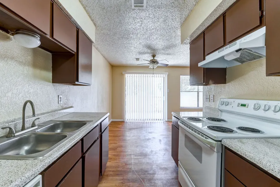 Kitchen with dark wood cabinets, a double sink and a patio door