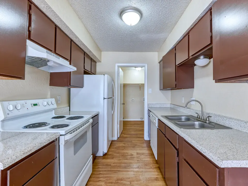 Galley kitchen with dark wood cabinets and white appliances