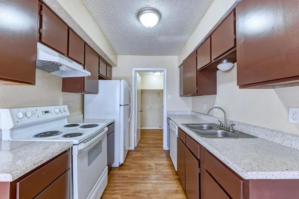 Galley kitchen with dark wood cabinets and white appliances
