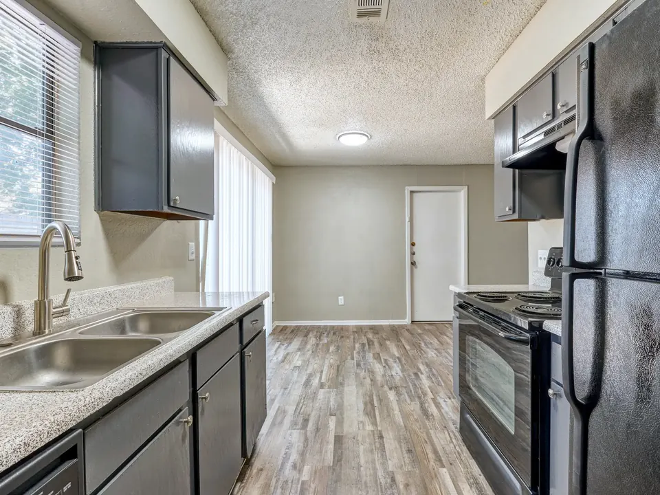 Renovated kitchen with grey cabinets and black appliances in a 3-bedroom Modern Grey townhome