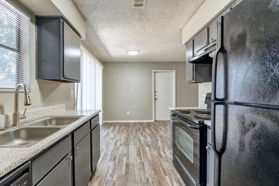 Renovated kitchen with grey cabinets and black appliances in a 3-bedroom Modern Grey townhome