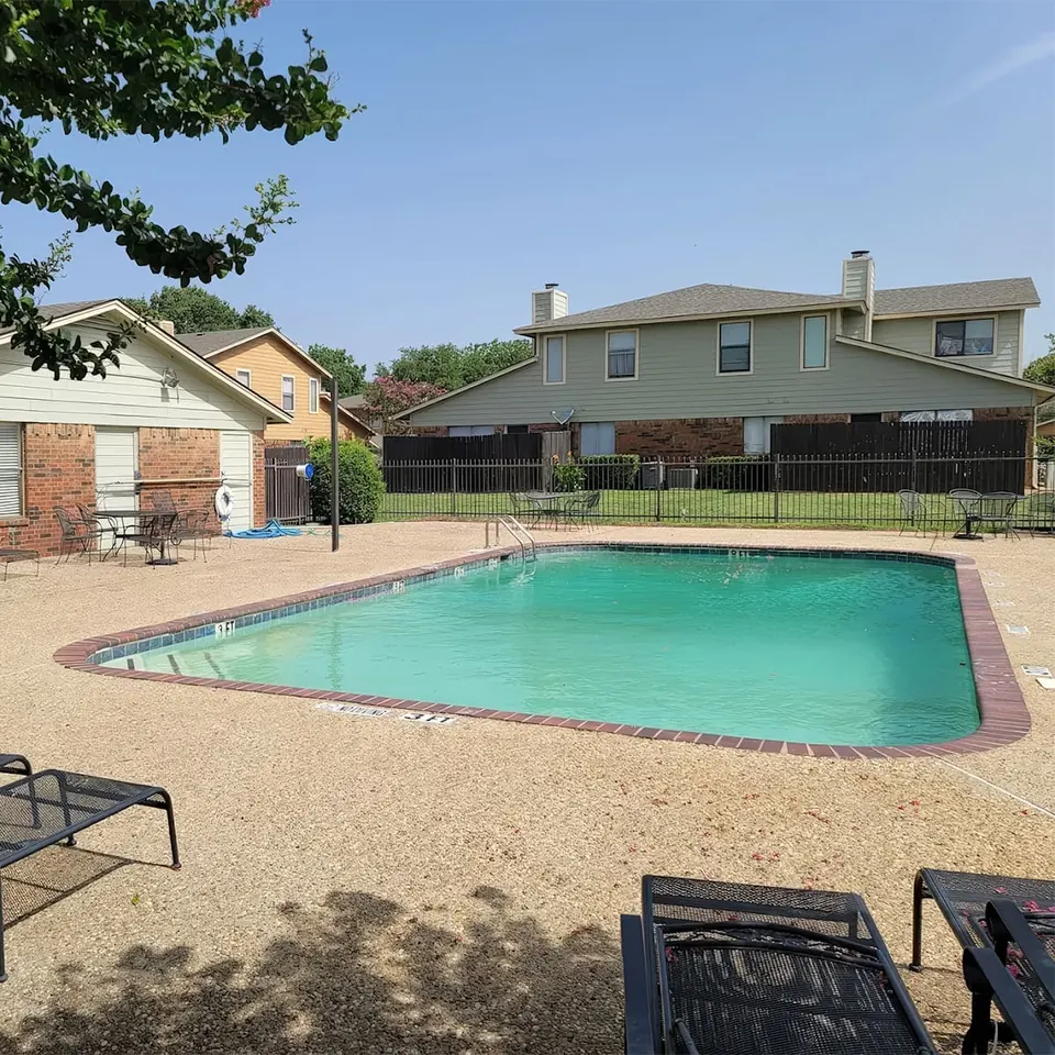 Pool with lounge chairs next to two-story townhomes