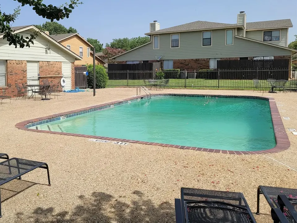 Pool with lounge chairs next to two-story townhomes