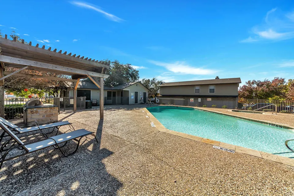 Pool deck with a pergola and grill at Cedar Ridge Townhomes